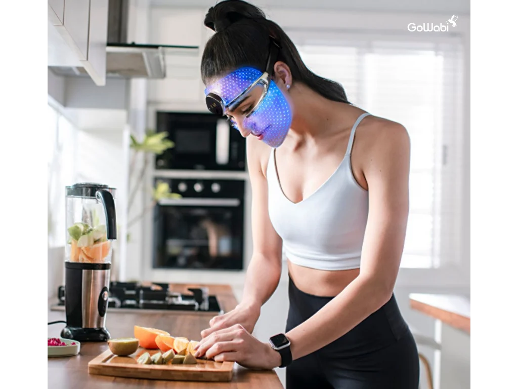 ผู้หญิงกำลังใช้ FAQ™ 202 LED Mask ขณะกำลังทำอาหาร